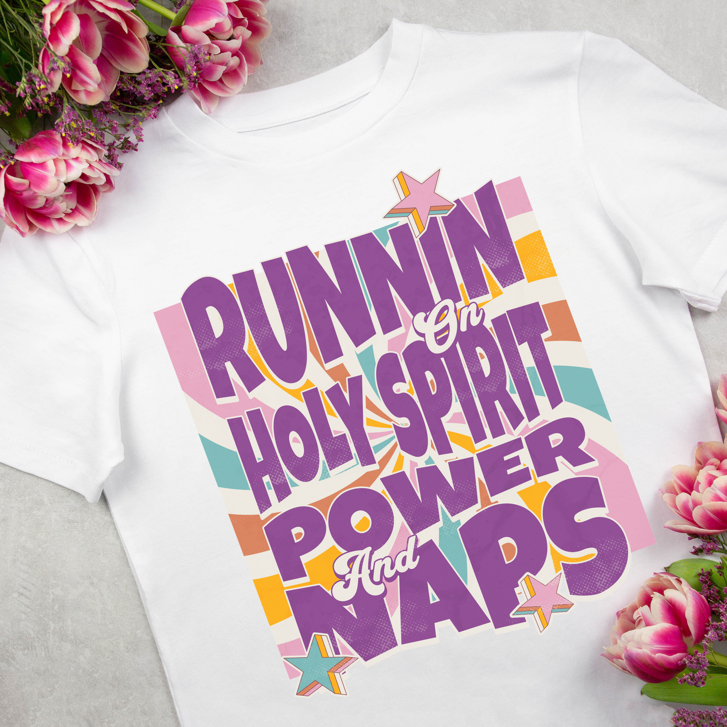 flat lay image of a womens christian streetwear funny christian t shirt that says runnin on holy spirit power and naps in a retro boho style design