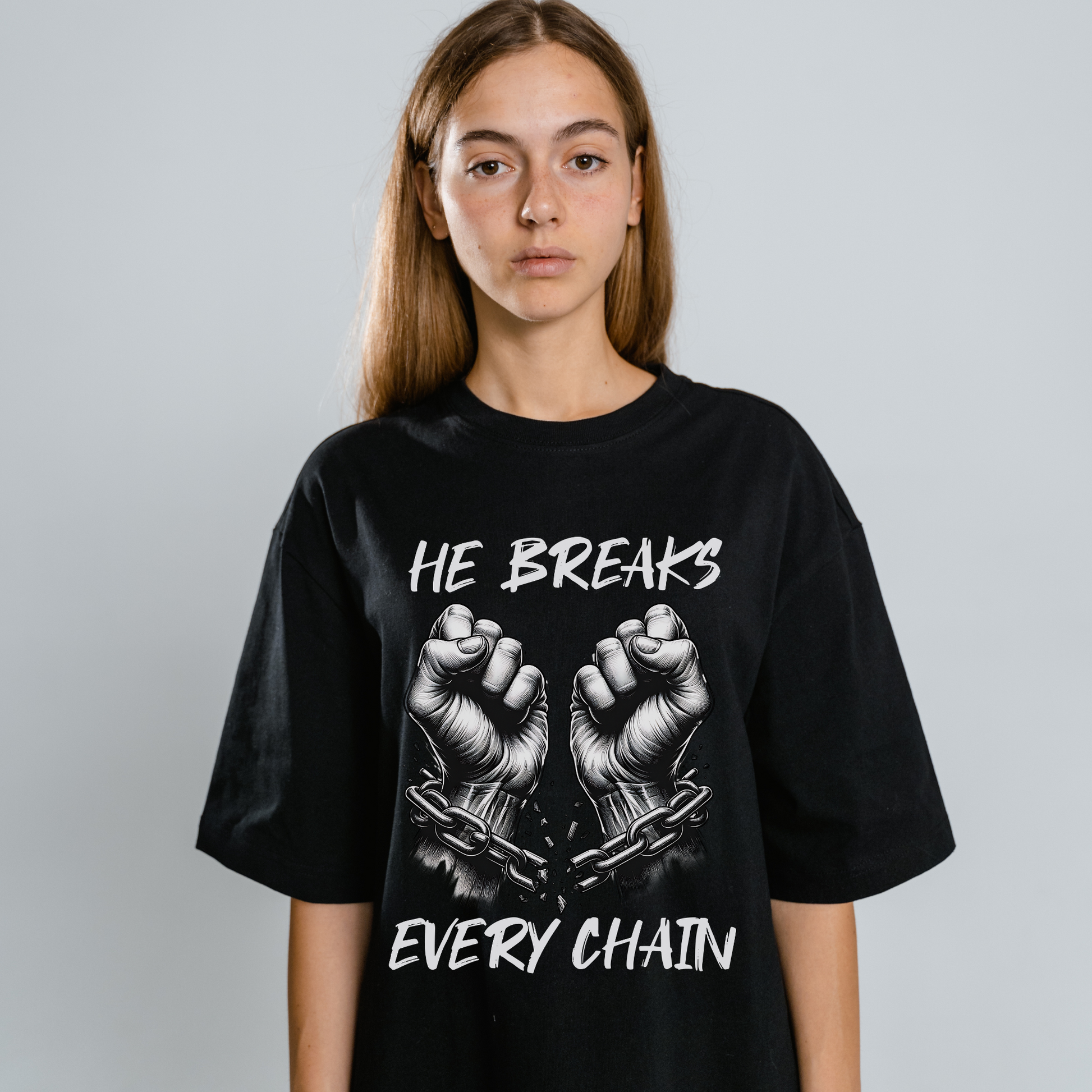 a women wearing christian apparel in a black short sleeve crew neck christian graphic tee that says he breaks every chain with the image of hands breaking free from chains