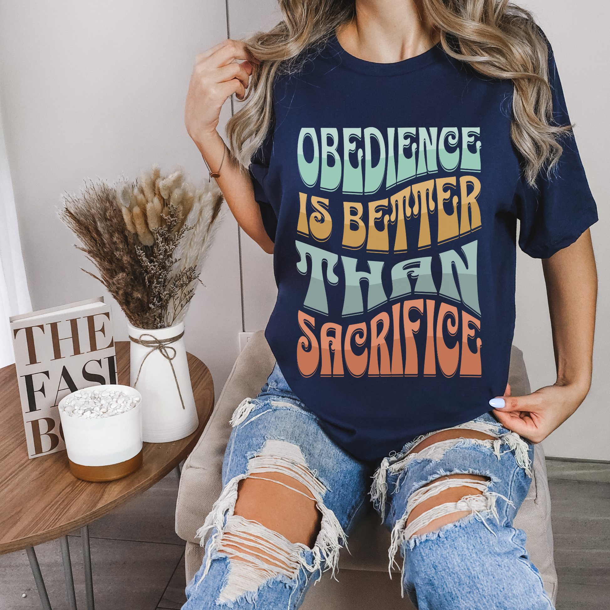 women wearing christianity clothing in a navy short sleeve crew neck graphic tshirt that says obedience is better than sacrifice